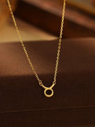 Gold necklace with a small round pendant on a brown background
