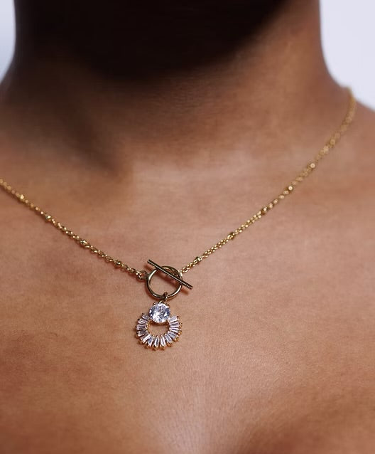 Gold necklace with a pendant on a person's neck