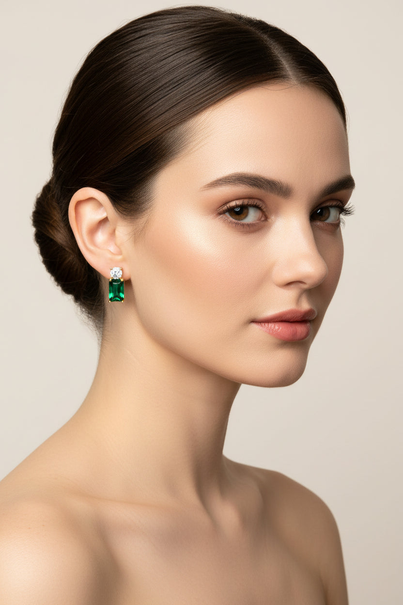 Woman wearing emerald green earrings against a neutral background