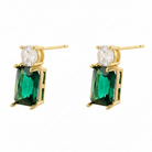 Gold earrings with emerald green gemstones on a white background