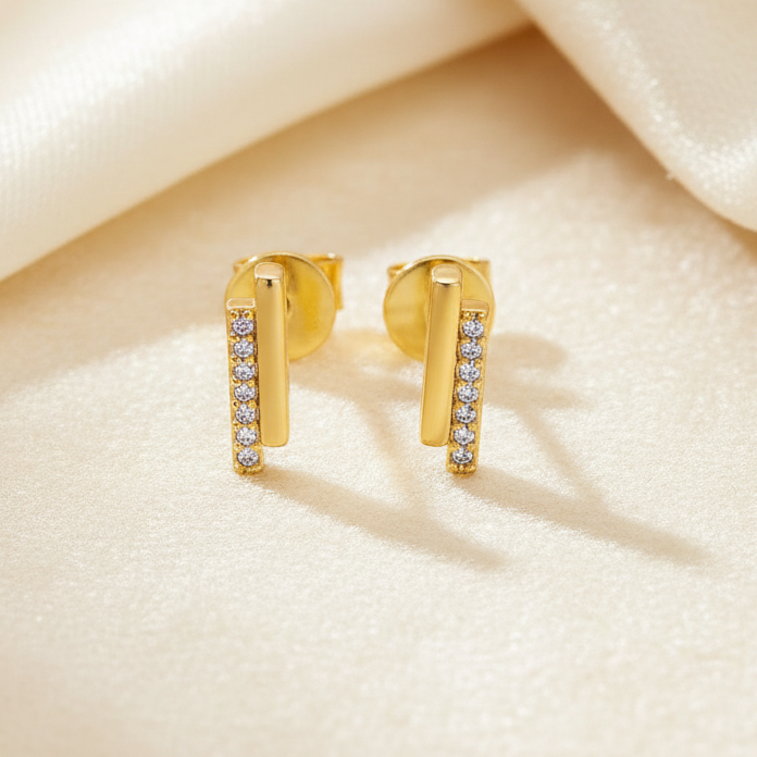 Gold hoop earrings with embedded stones on a soft beige fabric background