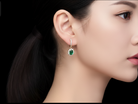 Close-up of a person wearing green earrings with a black interface overlay.