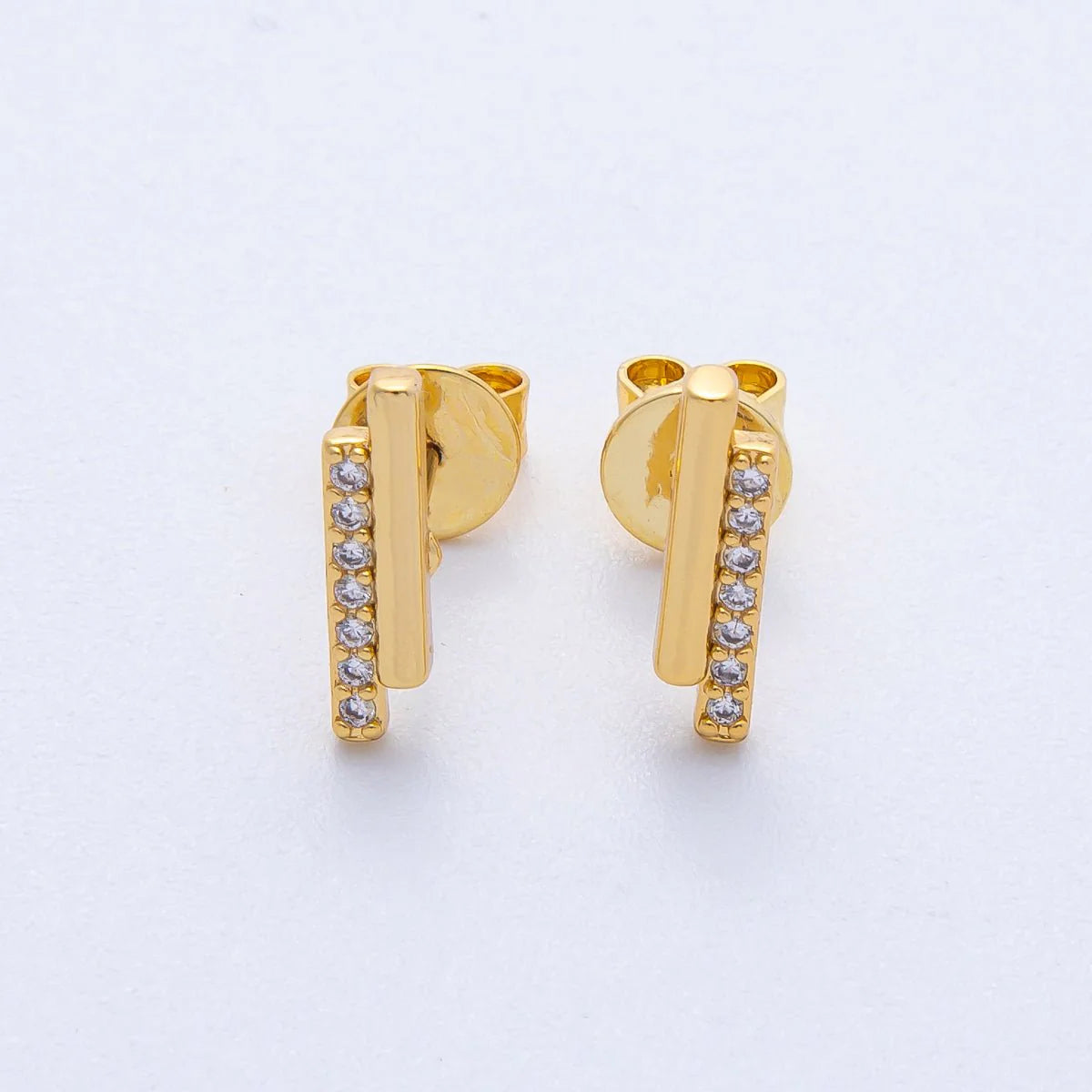 Gold earrings with small diamonds on a light gray background