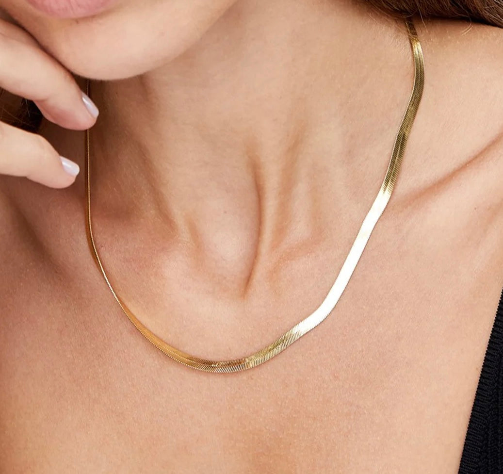 Gold necklace being worn on a person's neck