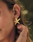 Close-up of a person wearing a gold starfish earring.