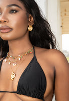 Woman wearing a black bikini top with gold jewelry outdoors