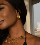 Woman wearing gold earrings and necklaces with a blurred background
