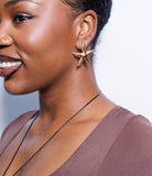 Woman wearing a chord necklace and starfish earring with a plain background