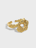 Gold ring with a textured design on a light gray background