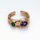 Gold open ring with green and purple gemstones on a white background