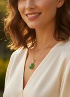 A photo of a woman wearing a green gemstone necklace on a white background.