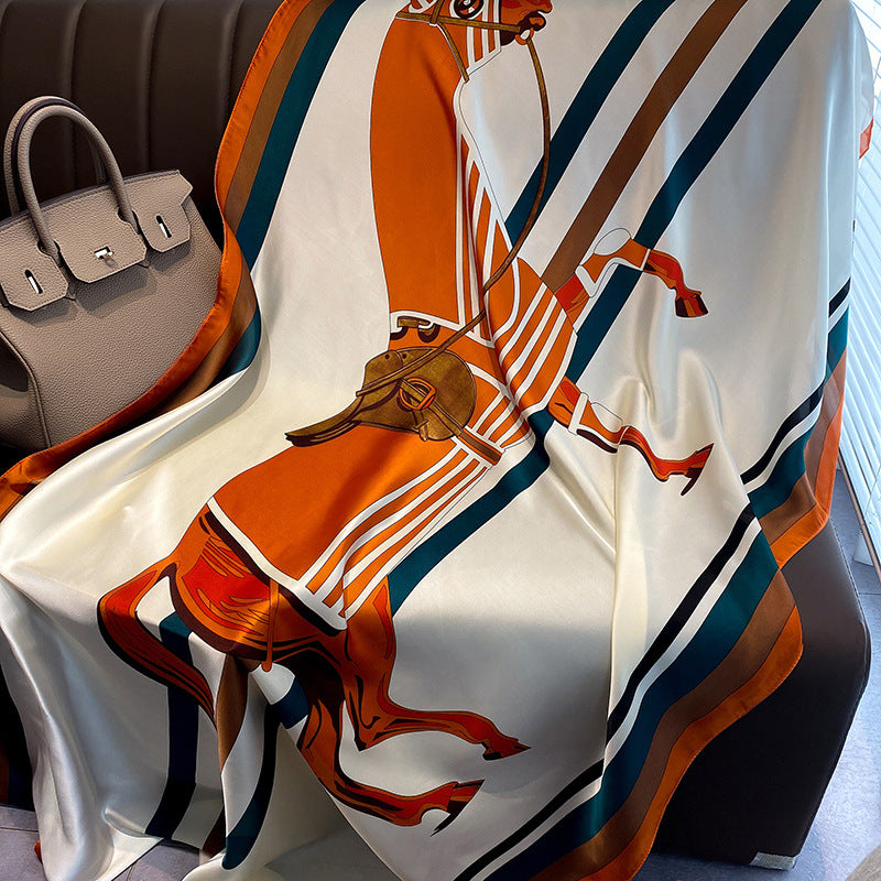 Decorative scarf with horse design draped over a chair, next to a handbag.