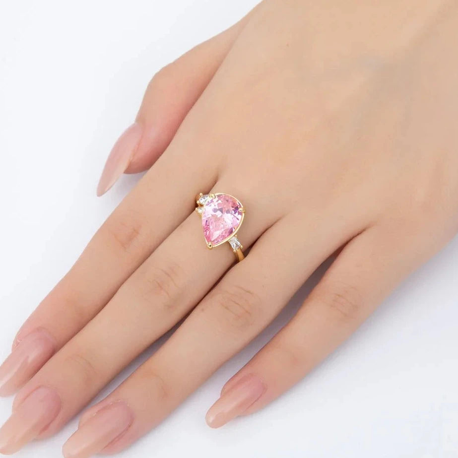 Hand wearing a ring with a pink gemstone on a white background
