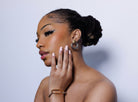 Woman wearing hoop earrings and a bracelet with a neutral background