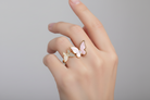 Hand wearing a butterfly-shaped ring on a plain background