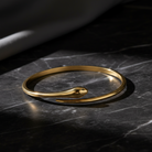 Gold snake-shaped bracelet on a dark marble surface
