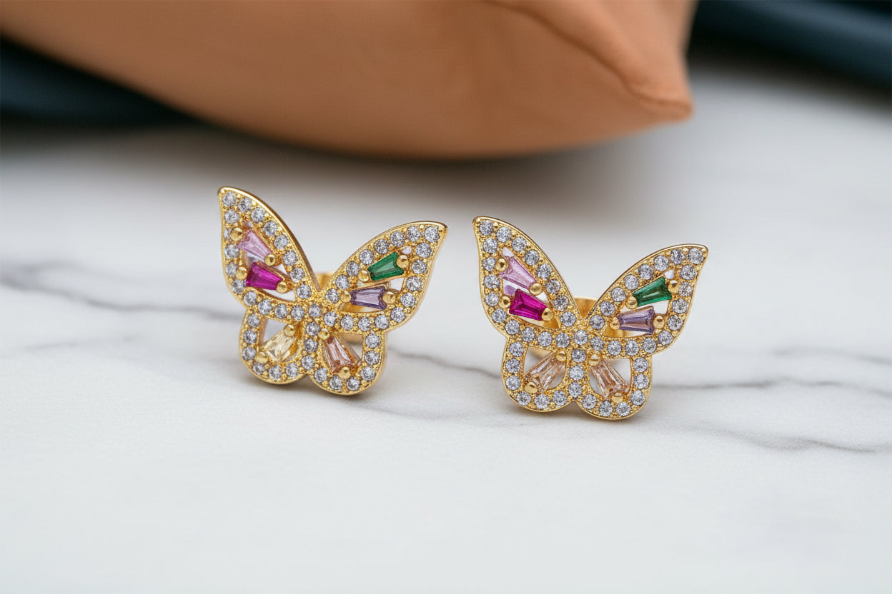 Butterfly-shaped earrings with gemstones on a light background