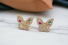 Butterfly-shaped earrings with gemstones on a light background