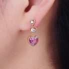 Heart-shaped earring with purple gemstone worn on an ear