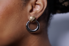 Close-up of a person wearing a silver hoop earring with gold accents.