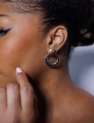 Close-up of a person wearing a gold hoop earring with a blurred background