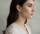 Person wearing irregular silver earrings with a neutral background