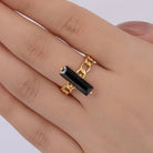 Gold ring with a black stone on a hand against a white background