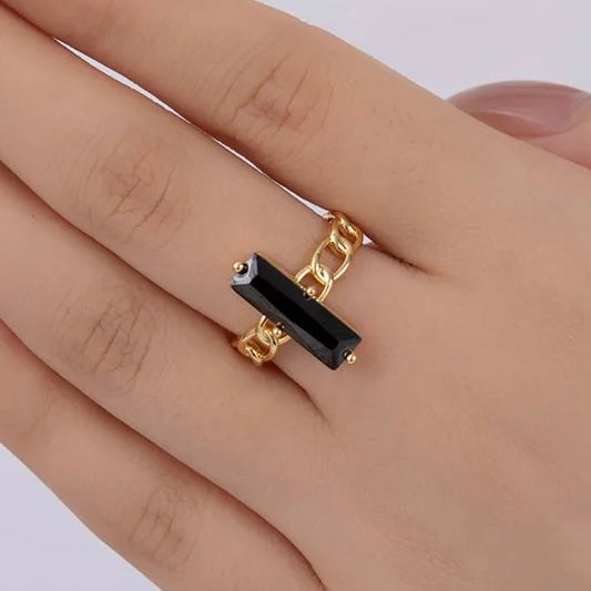 Gold ring with a black stone on a hand against a white background