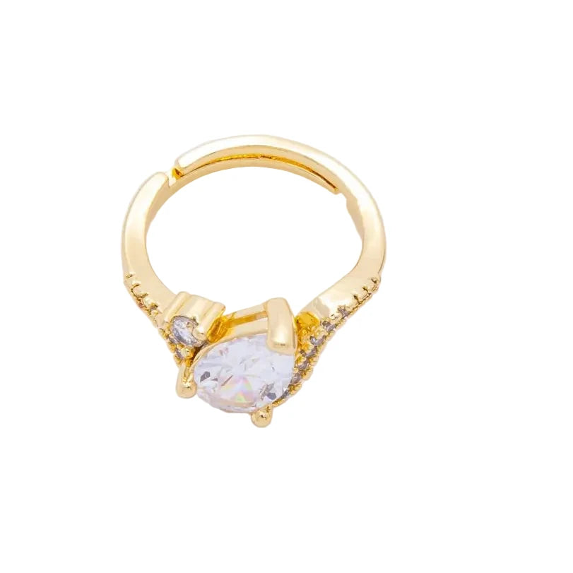 Gold ring with a clear gemstone next to a quarter on a white background