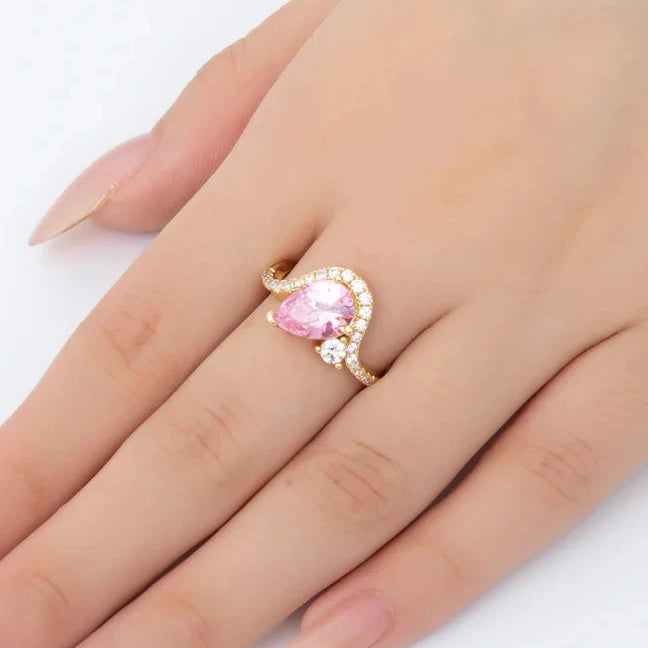 Hand wearing a ring with a pink gemstone on a white background