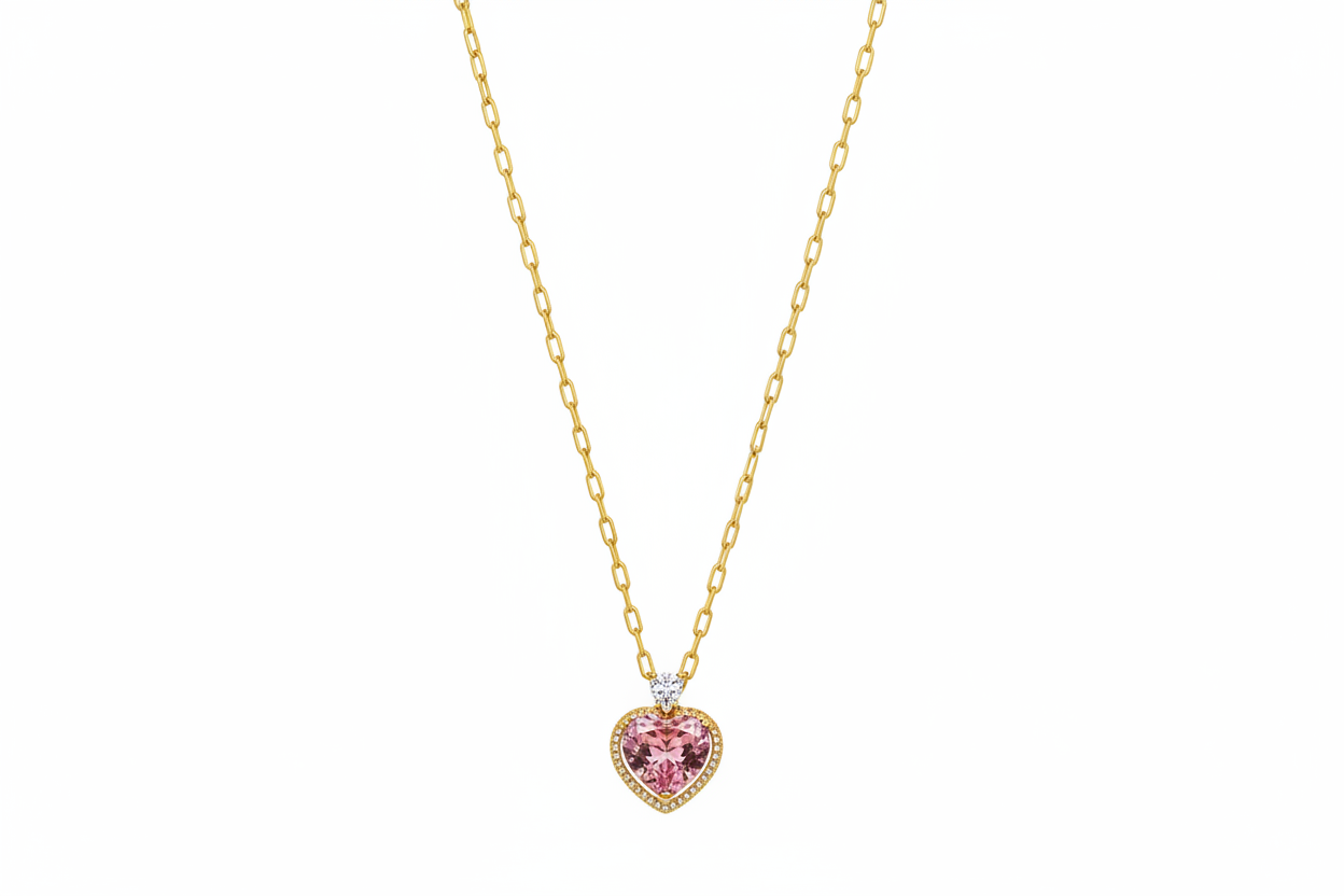 Heart-shaped pink gemstone necklace with gold chain on a beige background