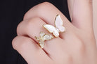 Butterfly-shaped rings on a hand against a dark background