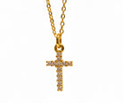 Gold cross necklace with pink gemstones on a white background