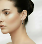 Woman wearing a silver earring with black stones against a neutral background