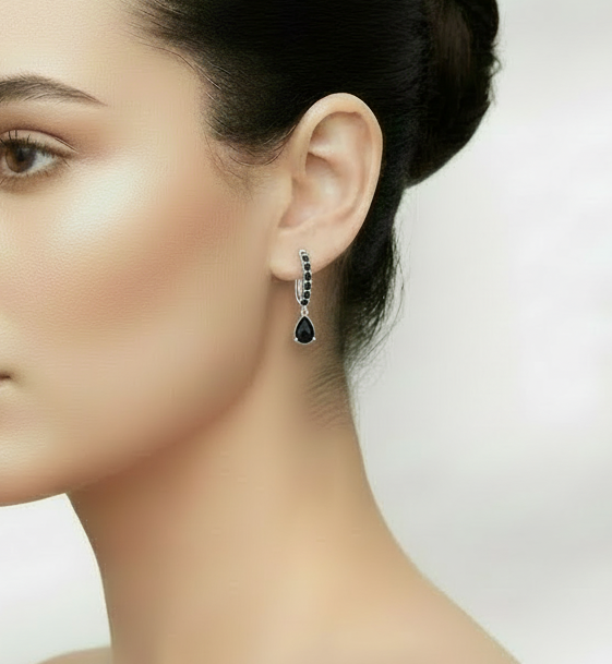 Woman wearing a silver earring with black stones against a neutral background