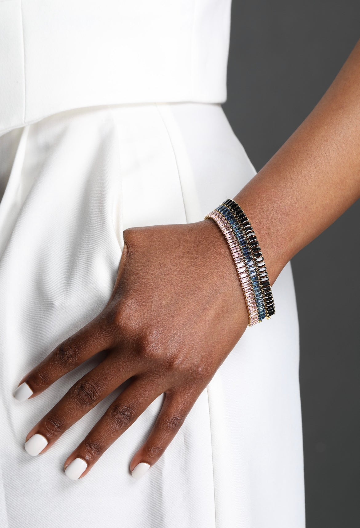 Hand wearing multiple bracelets with a white background