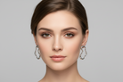 Woman wearing silver hoop earrings against a gray background