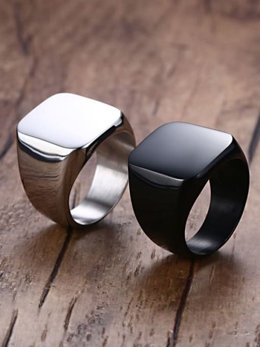 Two rings, one silver and one black, on a wooden surface.