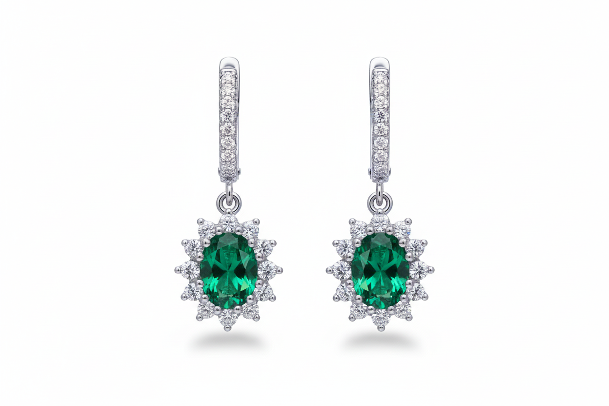 Pair of emerald green gemstone earrings with diamond accents on a white background