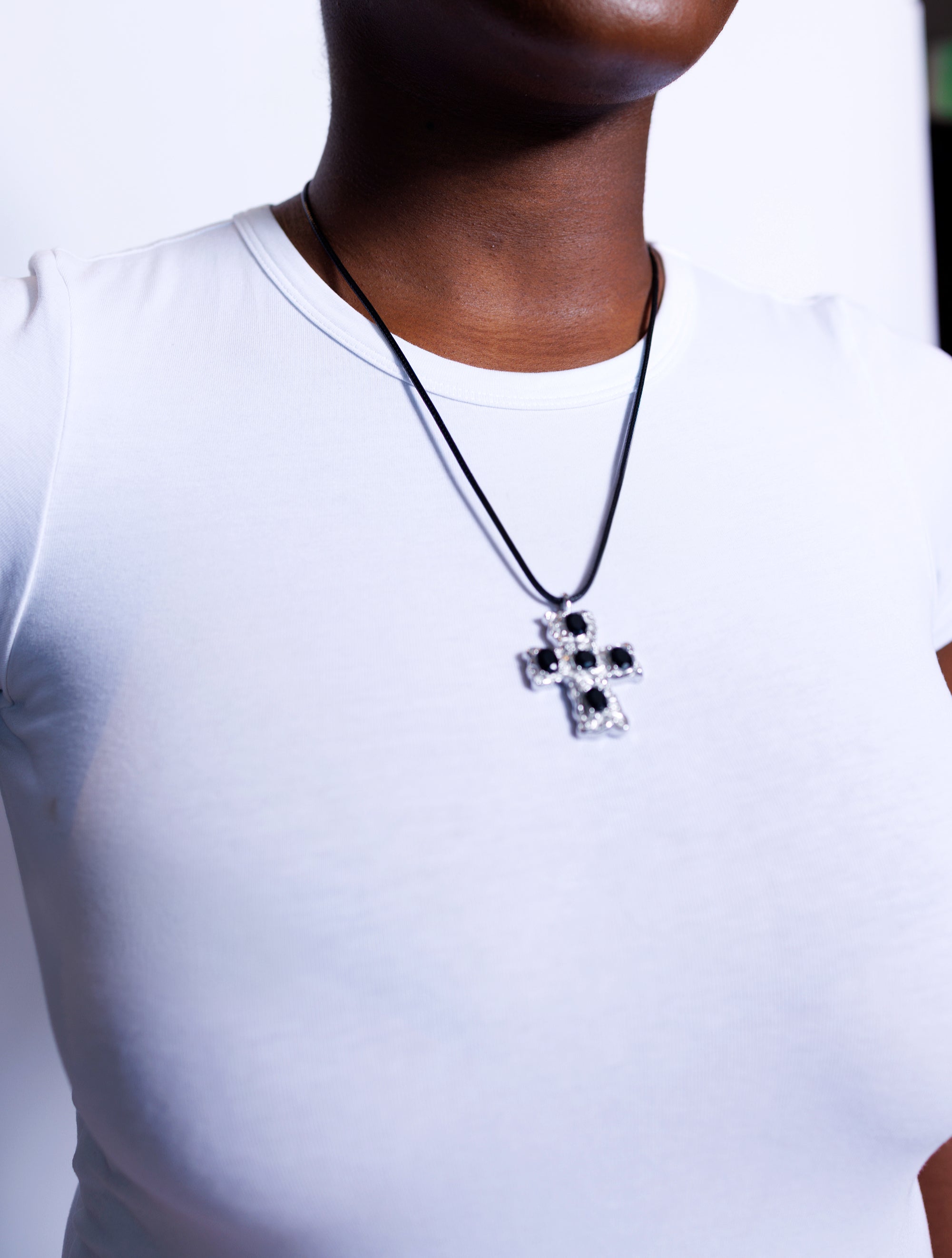 Person wearing a necklace with a cross pendant on a white background