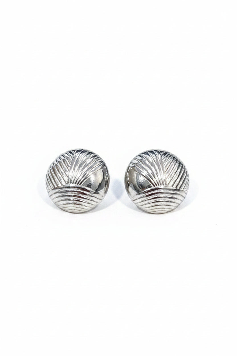 Pair of silver shell-shaped earrings on a textured beige surface