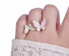 Butterfly-shaped rings on a finger with a white background