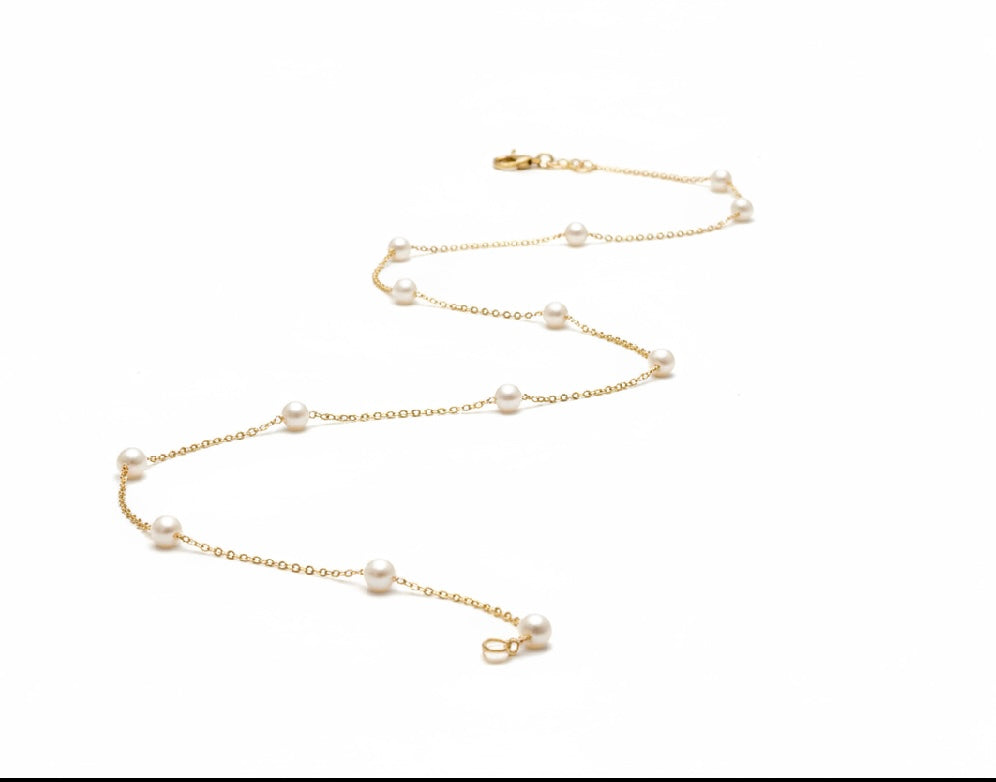 Gold necklace with pearls on a white background