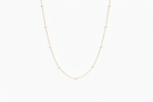 Gold necklace with small pearl beads on a light beige background