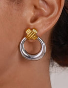 Gold and silver hoop earring worn by a person