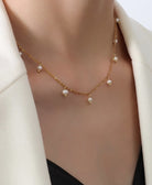 Gold necklace with pearls worn by a woman against a white background