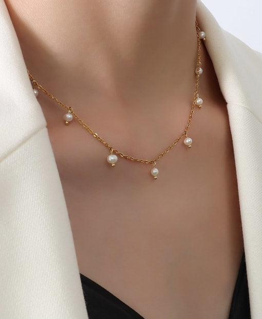 Gold necklace with pearls worn by a woman against a white background