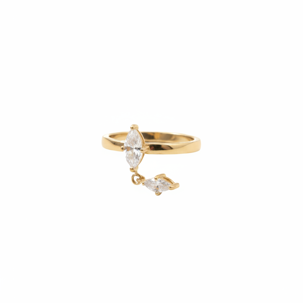 A gold ring featuring a marquise-cut clear gemstone and a smaller dangling marquise-cut gemstone, photographed on a clean white background.