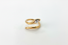 A gold snake ring with a small clear marquise-cut gemstone on its head, photographed on a plain white background.