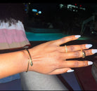 Hand with gold rings and bracelet against a blurred background